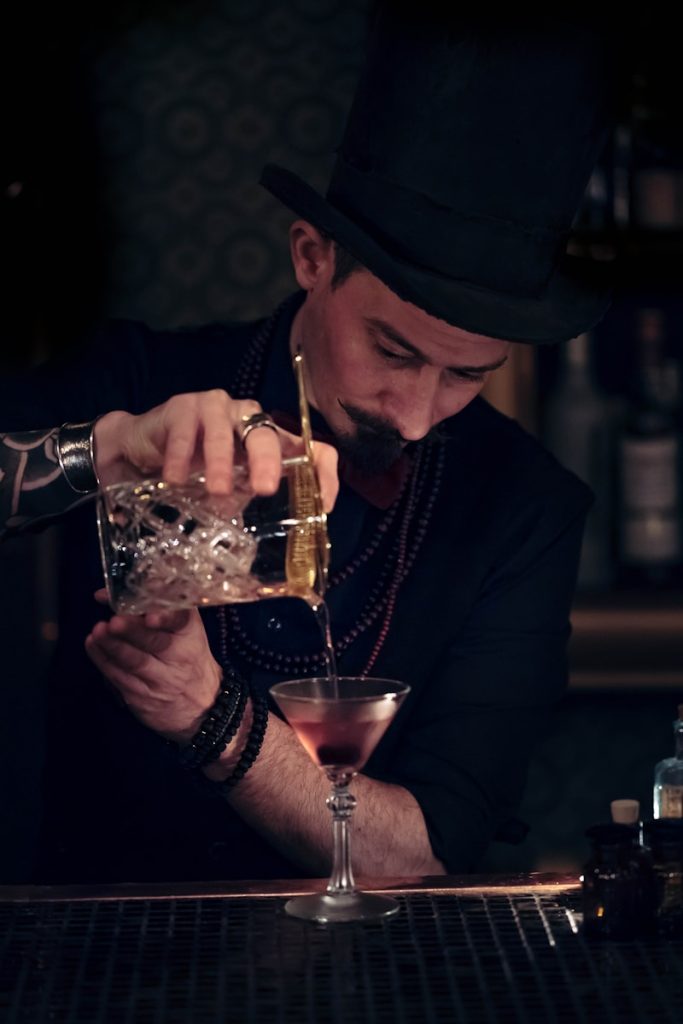 mężczyzna nalewa drinka do kieliszka